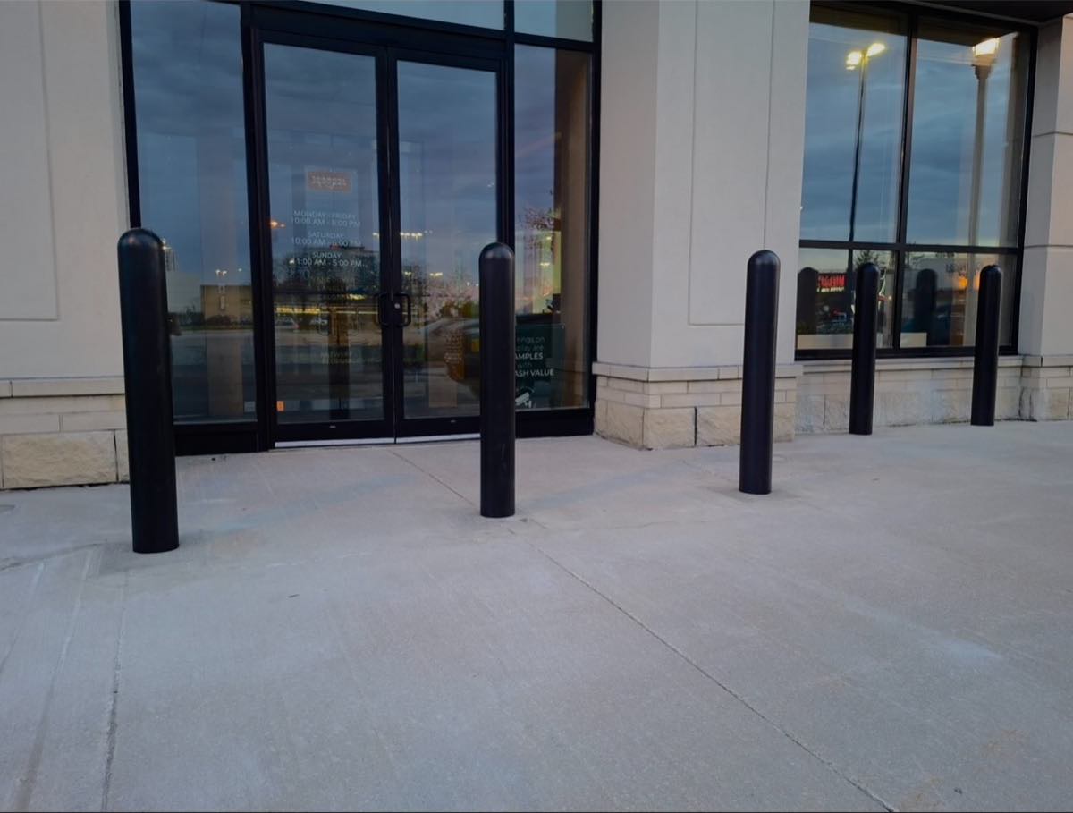 Black steel bollards outside a retail storefront